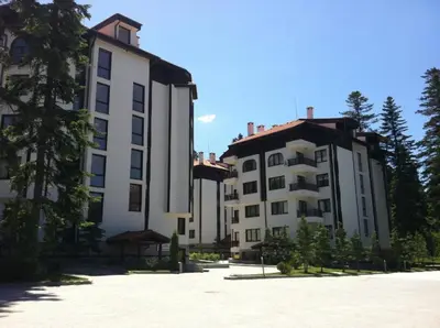 two large buildings in a parking lot with trees at Flora Clover One Bedroom Apartment nr. 18 in Borovets
