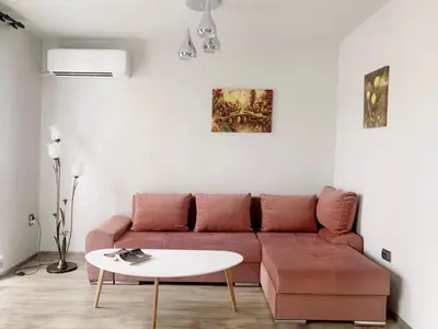 a living room with a red couch and a white table at Altavista mountain apartment in Samokov