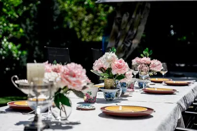 a long table with plates and vases of flowers on it at Къща за гости ЗЕЛЕНА in Vinogradets