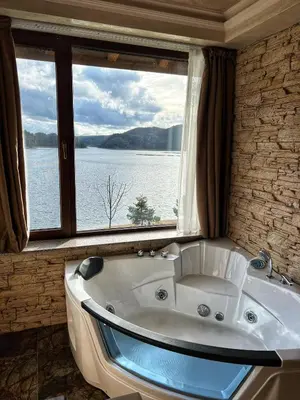 a bath tub in a room with a large window at OASIS RESORT RHODOPES in Dospat