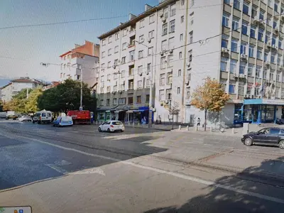 an empty street with cars parked in front of a building at Your home away from home in Sofia