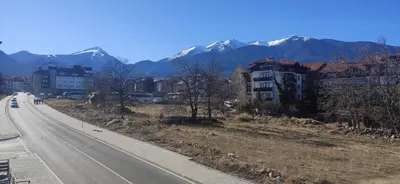 an empty road with buildings and mountains in the background at Apartment Pirin in Bansko