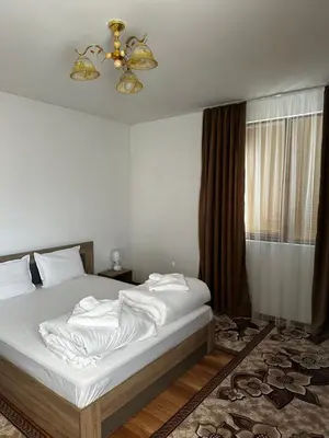 a bedroom with a bed with white sheets and a chandelier at Snow House in Bansko