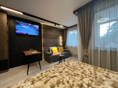 a bedroom with a large bed and a tv on a wall at Апартамент - Боровец Хотел ''Боровец Гардънс'' A 44 in Borovets