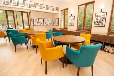 a dining room with tables and chairs and windows at Hotel Alpinist, Malyovitsa in Govedartsi
