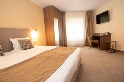 a hotel room with a large bed and a desk at Hotel Alpinist, Malyovitsa in Govedartsi