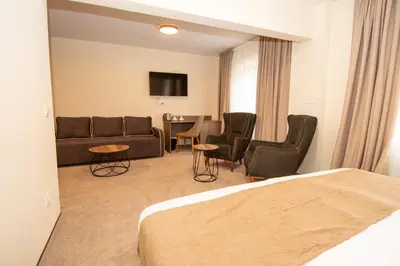 a hotel room with a bed and a couch and chairs at Hotel Alpinist, Malyovitsa in Govedartsi