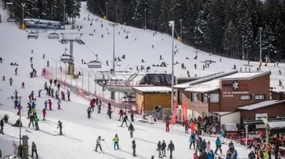 a group of people skiing down a ski slope at Апартамент B9 in Borovets