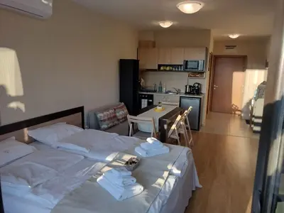 a bedroom with a white bed and a kitchen at Студио Пацо и Нина в AspenValley in Razlog