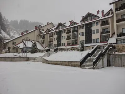 a snow covered parking lot in front of a building at Antonovi Apartments 2 in hotel Laplandia in Pamporovo
