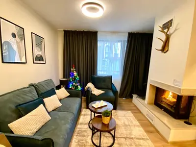 a living room with a green couch and a christmas tree at Antonovi Apartments 2 in hotel Laplandia in Pamporovo