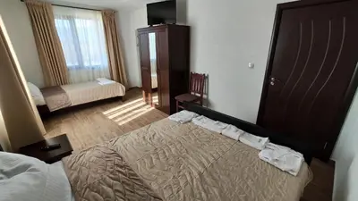 a hotel room with a bed and a television at Къща за гости - Вила Сидона in Banya