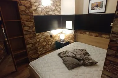 a small bedroom with a white bed with a stone wall at Boutique & artistic 3 bedroom apartment. in Pamporovo