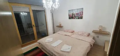 a small bedroom with a bed and a chandelier at Penthouse Harriet Bansko in Bansko