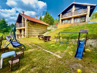 a house with a playground in front of a house at Къщи за гости Фантазия in Dospat