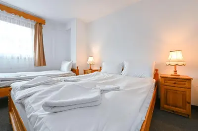 a bedroom with two beds with white sheets and a window at Хотел Феникс in Chepelare