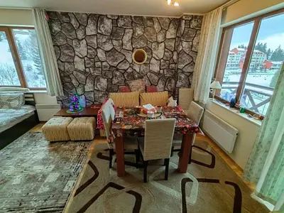 a dining room with a table and a stone wall at Apartment Love Pamporovo in Pamporovo