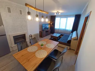 a dining room table with chairs and a living room at Viva 4 Apartment ski to the door complex Grand Monastery Pamporovo in Pamporovo