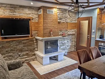 a living room with a stone fireplace and a tv at Mila VIP Apartment in Bansko