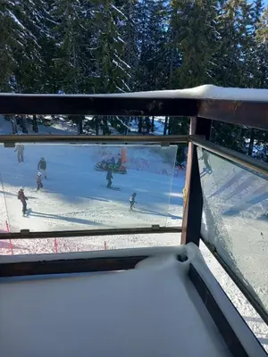 a view through a window of people skiing in the snow at Апартамент в хотел Стената, Пампорово in Smolyan