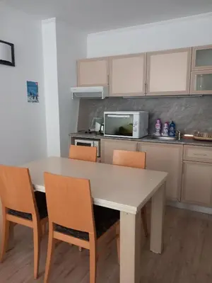 a kitchen with a table and chairs and a microwave at Апартамент в хотел Стената, Пампорово in Smolyan