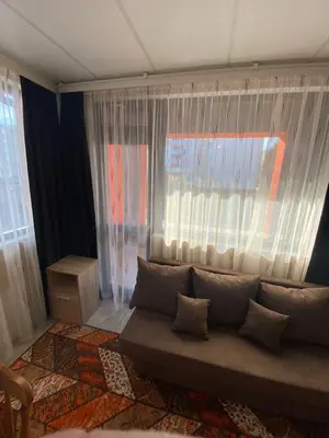 a living room with a couch in front of a window at Apartments EMIZA in Samokov