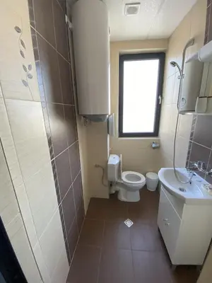 a bathroom with a toilet and a sink and a window at Apartments EMIZA in Samokov