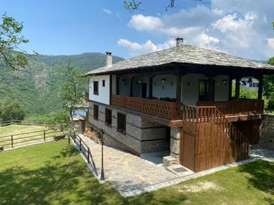 a large house with a deck on a field at Vladimirov's House Kovachevitsa , Цяла къща in Kovachevitsa
