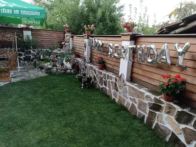 a retaining fence with a stone wall with flowers and a dog at Petar Guest House in Bansko