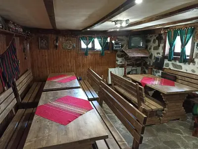 a dining room with wooden tables and benches in a house at Petar Guest House in Bansko