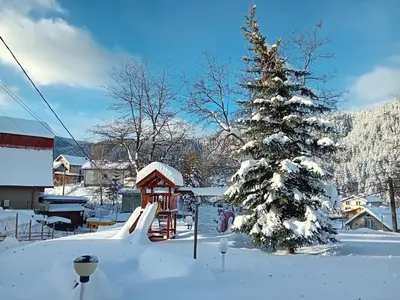 a snow covered yard with a christmas tree and a playground at Studio apartment with mountain view at Eagle Rock complex in Beli Iskar