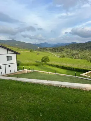 a white building in a field with mountains in the background at Вила ИГЛИКА in Yagodina