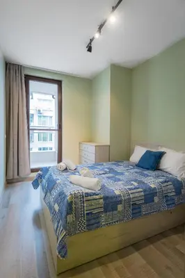 a bedroom with a bed with a blue blanket and a window at Intelligent Elephant Home - 1BDR Apartment by Flat Mаnager in Sofia