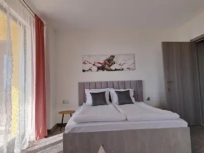 a bedroom with a large bed with a red curtain at Sunset view guest house in Ilindentsi