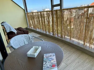 a table with a book sitting on a balcony at Panoramic Terrace City View Suite in Sofia Center in Sofia