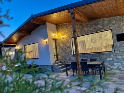 a patio with a table and chairs under a roof at Вила Рафаела-Мартина in Dobrinishte