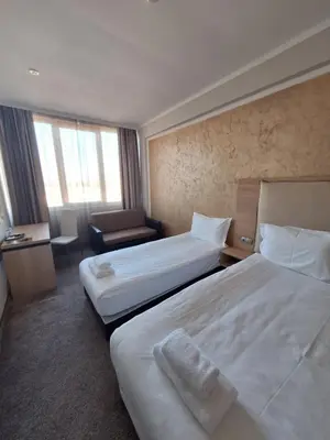 a hotel room with two beds and a chair at Hotel CITY Sandanski in Sandanski