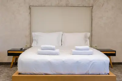 a white bed with two pillows on top of it at Hotel CITY Sandanski in Sandanski