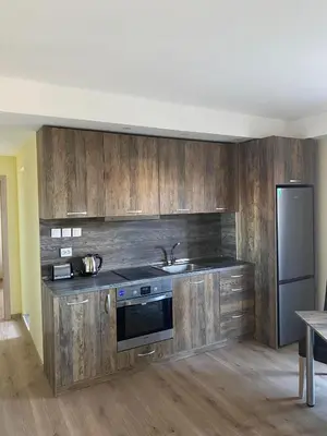 a kitchen with wooden cabinets and a sink and a refrigerator at Grand Apartments in Bansko
