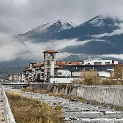 a city with a clock tower with a mountain in the background at Belvedere Holiday Club К302 in Bansko