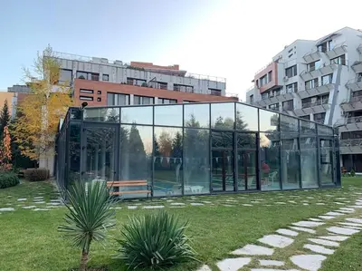 a glass building with a bench in a park at SliverCity next to paradise mall in Sofia