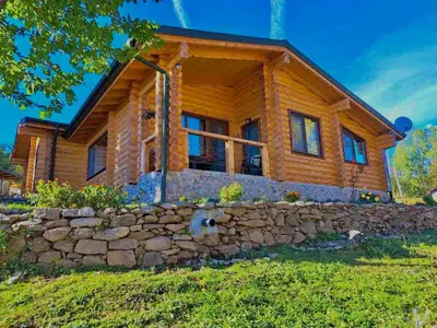 a log home with a stone wall at Вила Брезите in Pamporovo