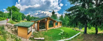 a log cabin in a park with a green roof at Вила Брезите in Pamporovo