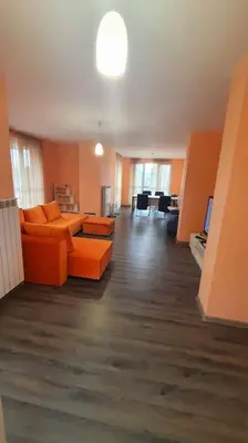 a living room with an orange couch and a table at Елегантен градски апартамент с обширна тераса in Pernik