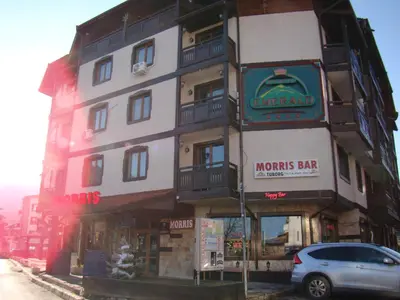 a building with a car parked in front of it at Dino privates apartments Emerald in Bansko