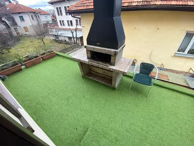 a green yard with a fireplace and a chair on it at House Trivia in Bansko