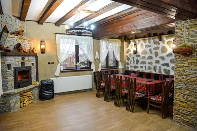 a dining room with a table and chairs and a fireplace at Къщи за гости НЕСИ in Leshten
