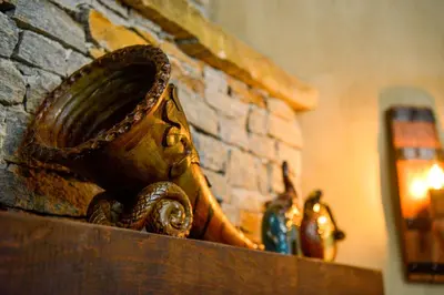 a mortar and pestle on a shelf next to a fireplace at Къщи за гости НЕСИ in Leshten