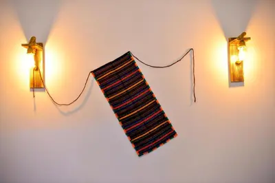 a striped tie hanging on a wall with two lights at Къщи за гости НЕСИ in Leshten