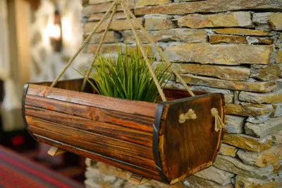 a wooden flower pot hanging on a stone wall at Къщи за гости НЕСИ in Leshten